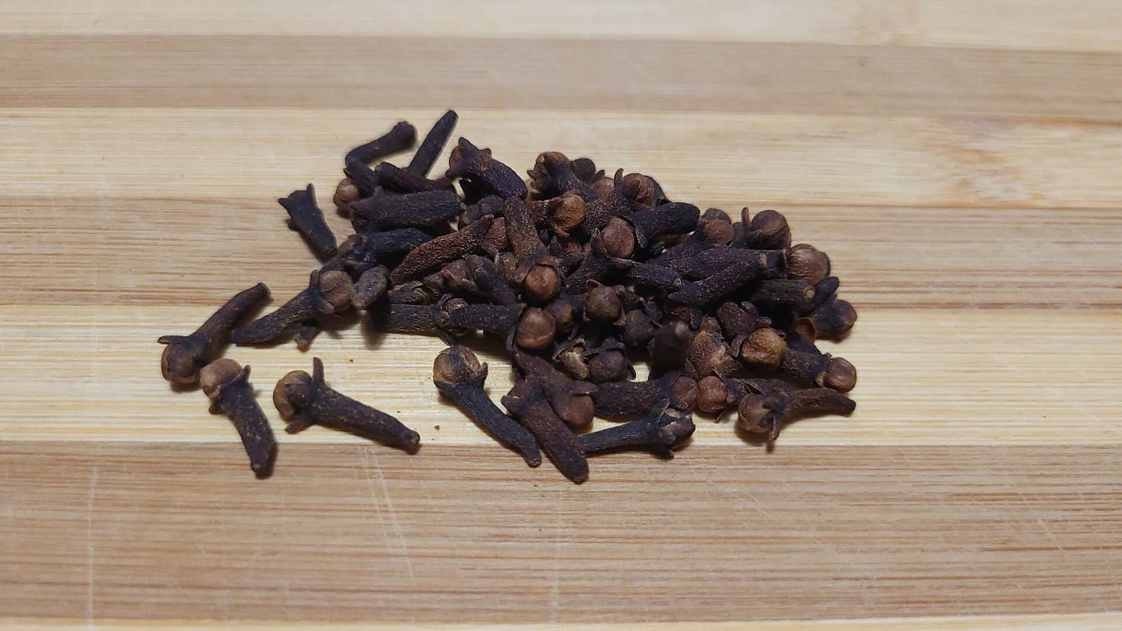 Sun-dried Zanzibar cloves spread on a woven mat with a hand sorting through them