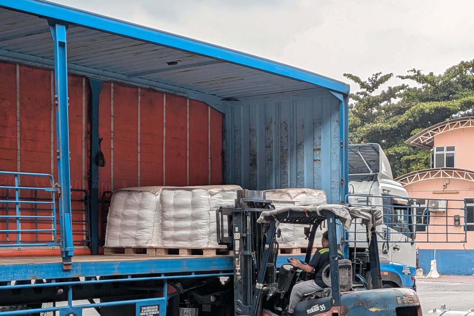 Forklift moving a palletised load towards a waiting vehicle