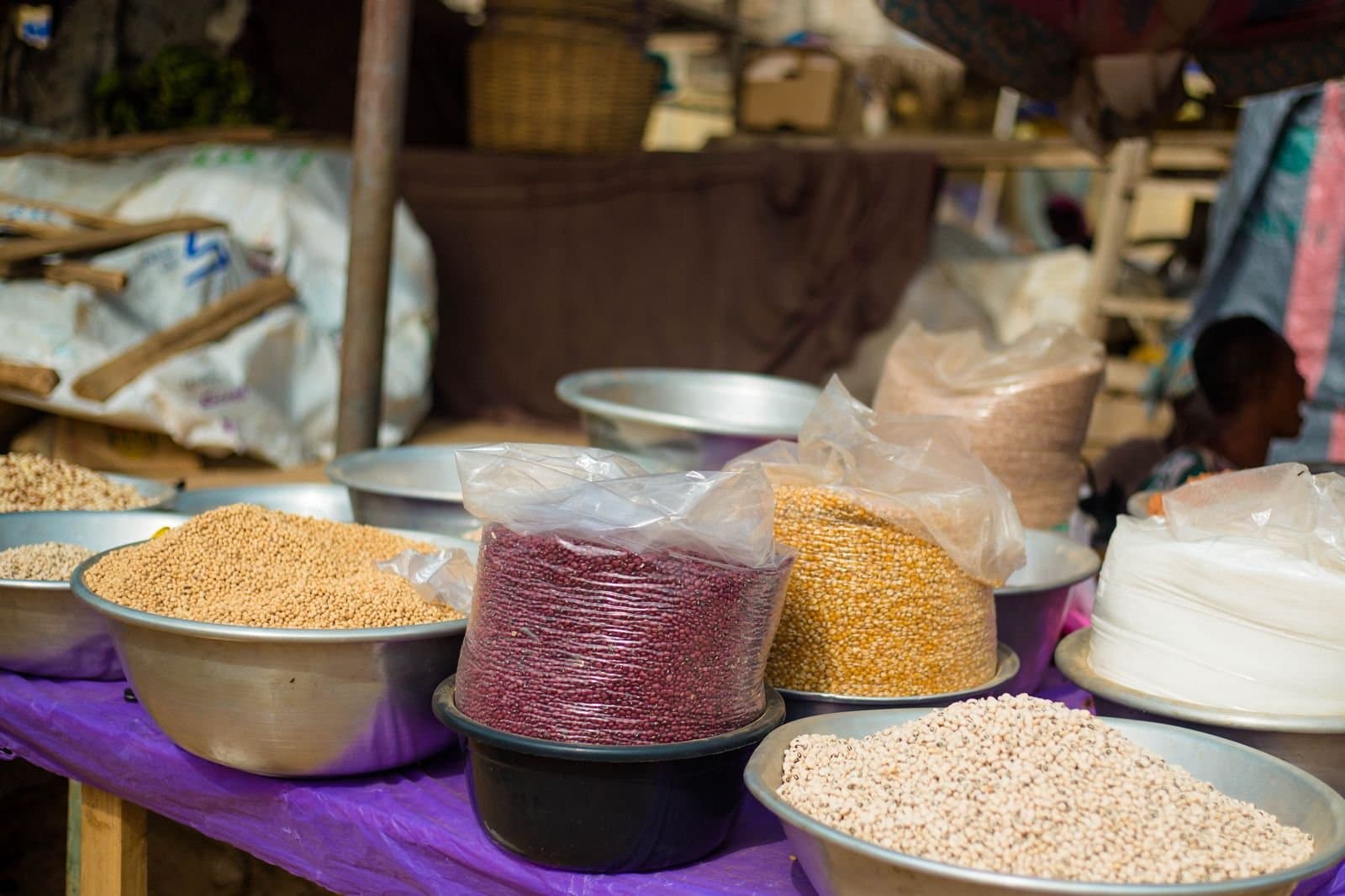Commodity samples laid out in open bowls on a market stand — soybeans, kidney beans, maize, cowpeas and rice side by side
