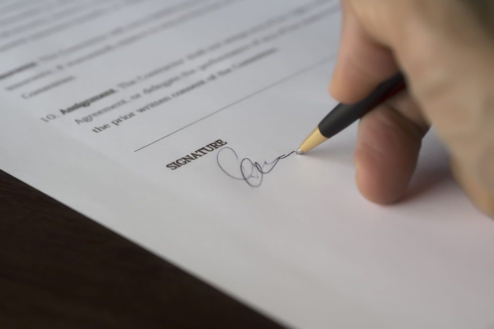 Close-up of a hand signing an agreement on the signature line
